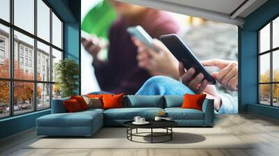 Group of young people using and looking at mobile phone while sitting together Wall mural