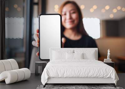 Mockup image of a beautiful asian woman holding and showing a mobile phone with blank white screen Wall mural