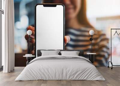 Mockup image of a beautiful asian woman holding and showing a mobile phone with blank white screen Wall mural