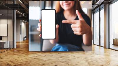 Mockup image of a beautiful woman pointing finger at a mobile phone with blank white screen Wall mural