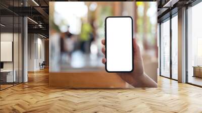 Mockup image of a hand holding and showing black mobile phone with blank white screen in modern cafe Wall mural