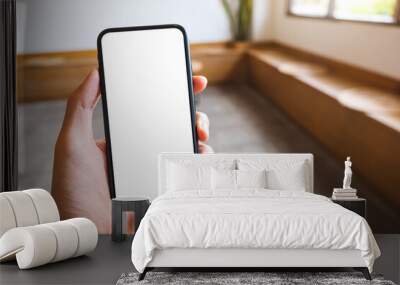 Mockup image of a hand holding and showing mobile phone with blank white screen in cafe Wall mural