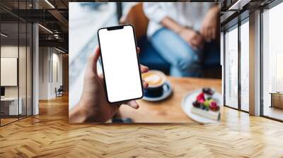 Mockup image of a man's hand holding mobile phone with blank white screen in cafe Wall mural