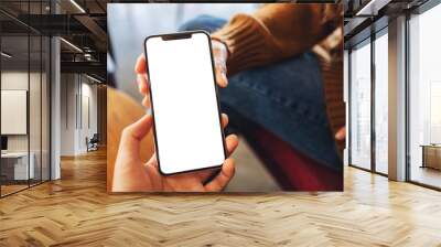 Mockup image of a woman holding and showing white mobile phone with blank black desktop screen to someone Wall mural