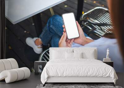 Mockup image of a woman holding and using mobile phone with blank desktop screen Wall mural