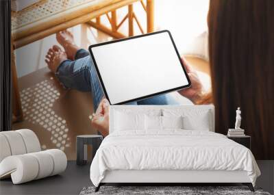 Mockup image of a woman holding and using tablet pc with blank desktop white screen at home Wall mural