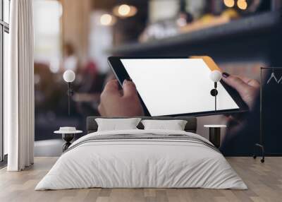 Mockup image of a woman holding black tablet pc with blank white desktop screen in cafe Wall mural