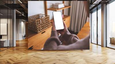 Mockup image of a woman holding mobile phone with blank desktop white screen at home Wall mural