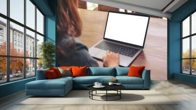 Mockup image of a woman using and touching on laptop touchpad with blank white desktop screen on wooden table Wall mural