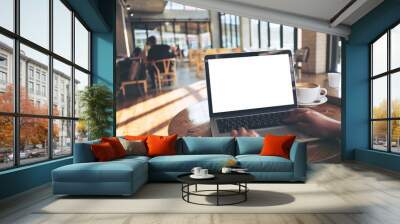 Mockup image of a woman using laptop with blank white screen on wooden table in modern loft cafe Wall mural