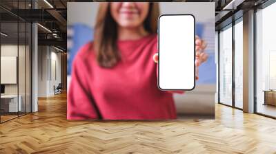 Mockup image of a young woman holding and showing a mobile phone with blank white screen Wall mural