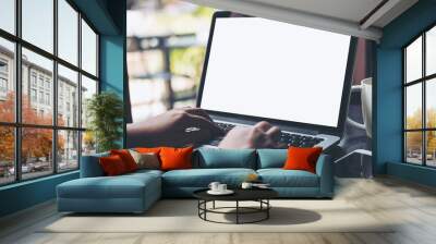 Mockup image of business woman using and typing on laptop with blank white screen and coffee cup on glass table in modern loft cafe Wall mural