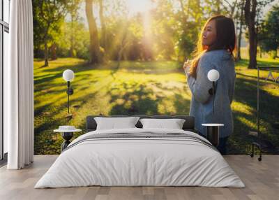 Portrait image of a beautiful asian woman standing among nature in the park before sunset Wall mural