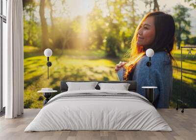 Portrait image of a beautiful asian woman standing among nature in the park before sunset Wall mural