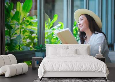 Portrait image of a beautiful young woman with hat reading book Wall mural