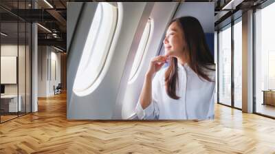 Portrait image of a woman looking through an airplane window Wall mural