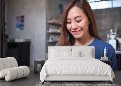 Portrait image of a young asian woman holding and looking at a glass of iced coffee Wall mural