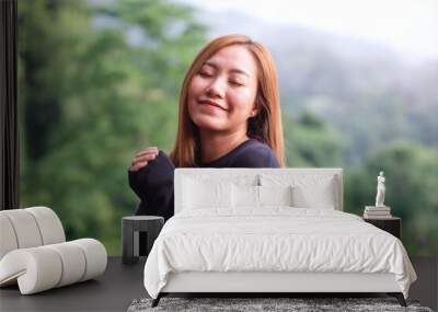 Portrait image of a young woman closed her eyes and enjoy a beautiful foggy mountain and nature view Wall mural