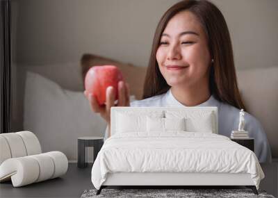 Portrait image of a young woman holding and looking at a red apple Wall mural