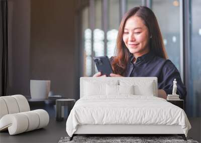 Portrait image of a young woman holding and using mobile phone in cafe Wall mural