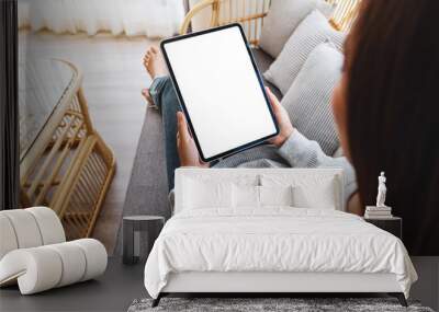 Top view mockup image of a woman holding black tablet pc with blank desktop white screen while lying on a sofa at home Wall mural