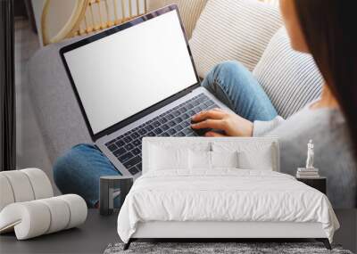 Top view mockup image of a woman working and typing on laptop computer with blank screen while sitting on a sofa at home Wall mural