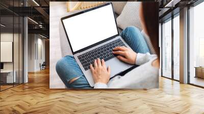 Top view mockup image of a woman working and typing on laptop computer with blank screen while sitting on a sofa at home Wall mural