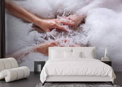 Close up top view of the hands of a couple in love taking a bath together with white foam. Lovers shake the water with soap to form foam. Newlyweds have fun on honeymoon weekend morning. Hand hygiene Wall mural