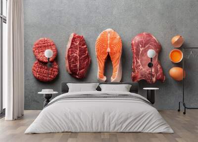 Carnivore or keto diet concept. Raw ingredients for zero carb or low carb diet - burger patties, ribeye, salmon steak, pork, egg on gray stone background.Top view or flat lay.Copy space top and bottom Wall mural