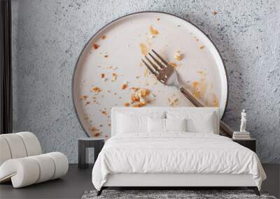 Empty dirty dish after cheesecake with caramel sauce and dessert fork. White rustic trendy modern fashionable dirty plate on gray cement background, top view or flat lay. Copy space for text Wall mural