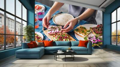 Female hands on dinning table. Young woman eat vegetarian toast. Vegan veggies sandwiches on dinning table Wall mural