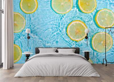 Lemon slices in clean transparent water over blue background with copy space. Water splashing on blue water surface in sunlight. Top view or flatlay. Summer, vacation, healthy eating concept Wall mural