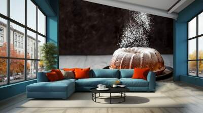 Woman's hand sprinkling icing sugar over fresh muffin cake. Powder sugar falls on fresh perfect muffin cake. Copy space for text. Ideas and recipes for breakfast or dessert Wall mural