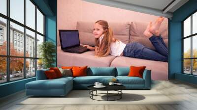 The child lies on the couch and works in a laptop computer Wall mural