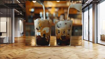 a picture showing the process of manually adding milk to two glasses of iced coffee. Wall mural