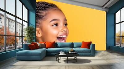 a young girl with long braided hair and mouth wide open, happy face against yellow background Wall mural