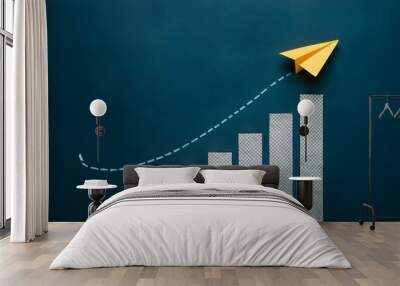 Yellow paper airplane over bar chart against blue backdrop symbolizes innovation and progress Wall mural