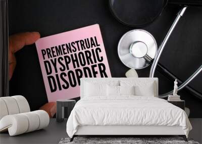 stethoscope and colored paper with the word premenstrual dysphoric disorder Wall mural