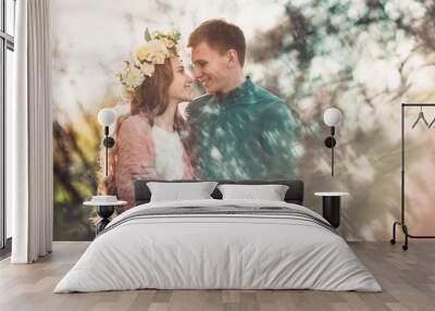 Love and tenderness. Beautiful young loving couple looking at eath other and smiling in blossom spring garden. Romantic dating. Wall mural