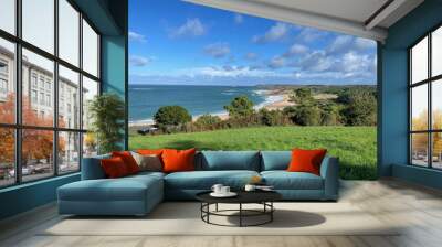 Landscape view of lush trees near the sandy beach with foamy waves against a blue sky Wall mural