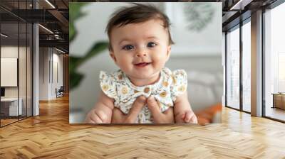 Adorable baby girl wearing floral dress being held and smiling at camera	 Wall mural