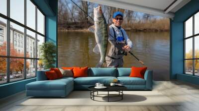 Happy fisherman with zander fish. Success walleye fishing at wild river Wall mural