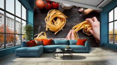 Female hands making fresh homemade pasta. Pasta ingredients on the dark wooden table top view Wall mural