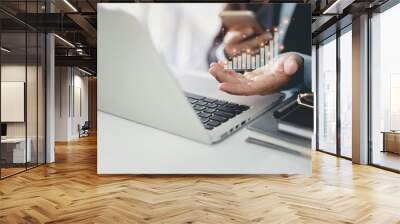 Business man in black suit sitting and working on computer and mobile phone. Man hands showing business growth and success result in virtual chart diagram with future growing plan. Wall mural