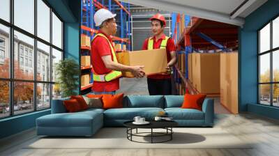 Group of warehouse workers men with hardhats and reflective jackets carrying a large box for delivery to production stock and inventory in retail warehouse logistics, distribution center Wall mural