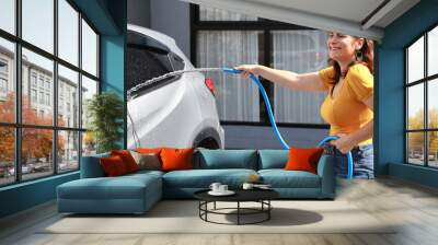 Happy young caucasian family with glove and microfiber washing or polishes car while looking away. Happiness moment of lovely family when cleaning car together in the house on sunny day outdoor Wall mural