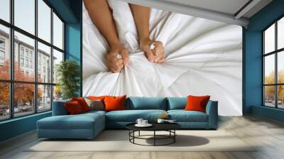 Top view young sexy woman hands pulling white sheets in ecstasy in hotel. Cute girl doing sign orgasm on white bed (sex and erotic concept for advertisement) Wall mural