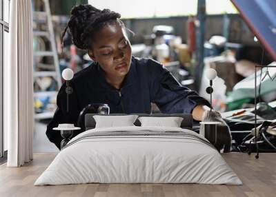 Woman technician car mechanic in uniform checking maintenance car service at repair garage station. Worker holding flashlight and wrench fixing breakdown vehicle. Concept of car center repair service. Wall mural