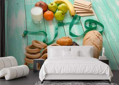 fruit with Cup of yogurt and bread separated by a measuring tape with chocolate and donuts on a green wooden background, concept of proper nutrition Wall mural