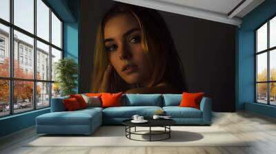 A young woman with long blonde hair looks directly at the camera. Wall mural